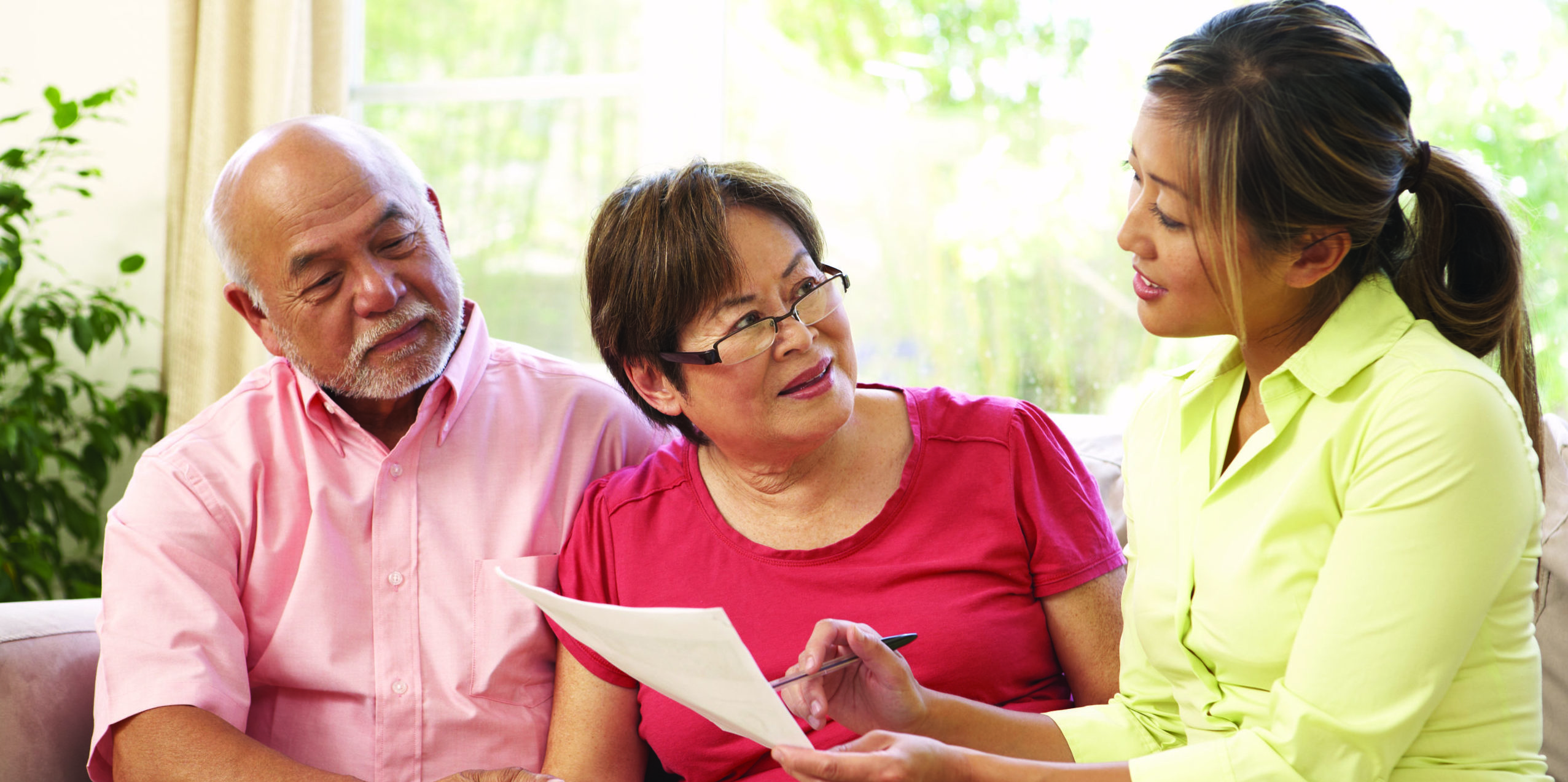 A woman helps an older adult couple with forms