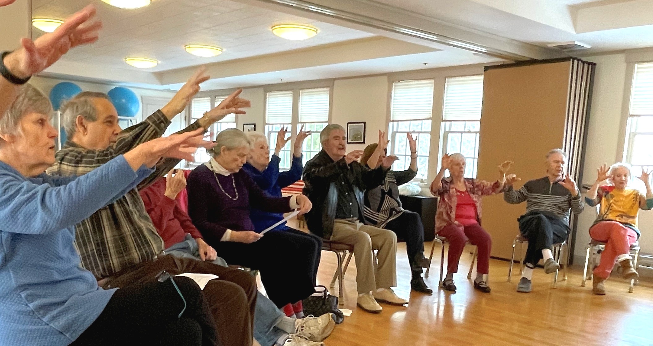 group of people seated with arms in the air to participate in musical show