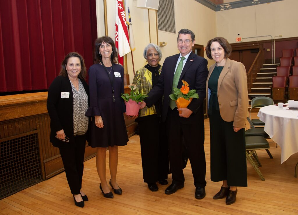 Group of MVES and AARP officials smiling and holding flowers from ceterpieces