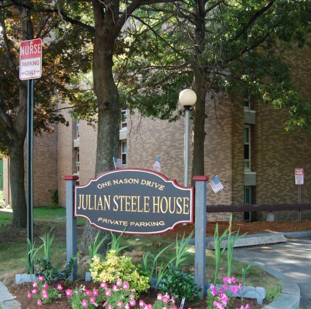 City building surrounded by trees with sign in front that says Julian Steele House